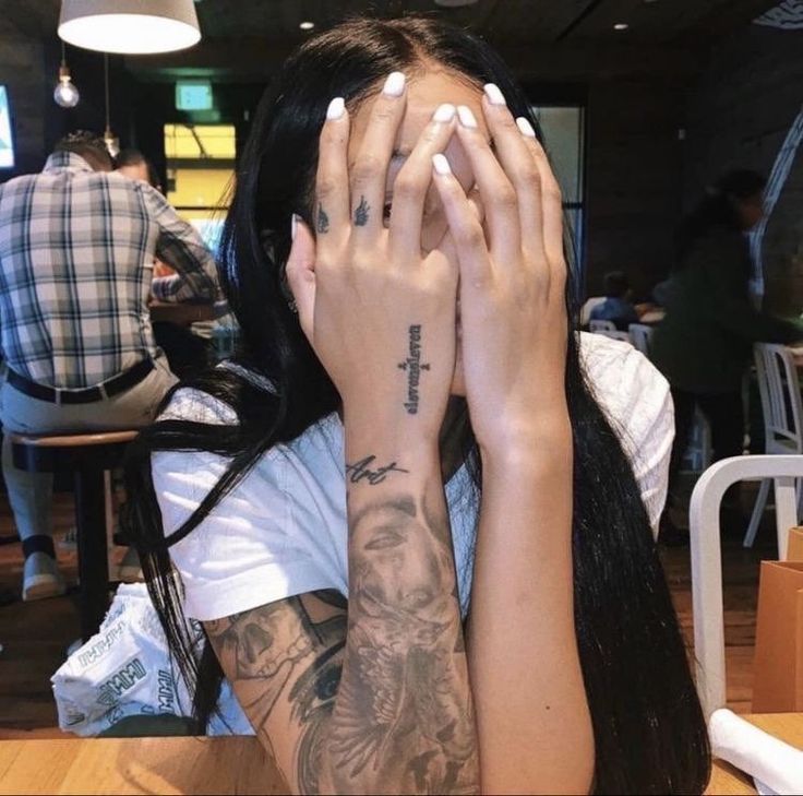 a woman sitting at a table with her hands covering her face