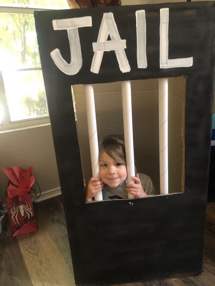 a young child is looking through a jail cell door with bars on it and the word jail written in white