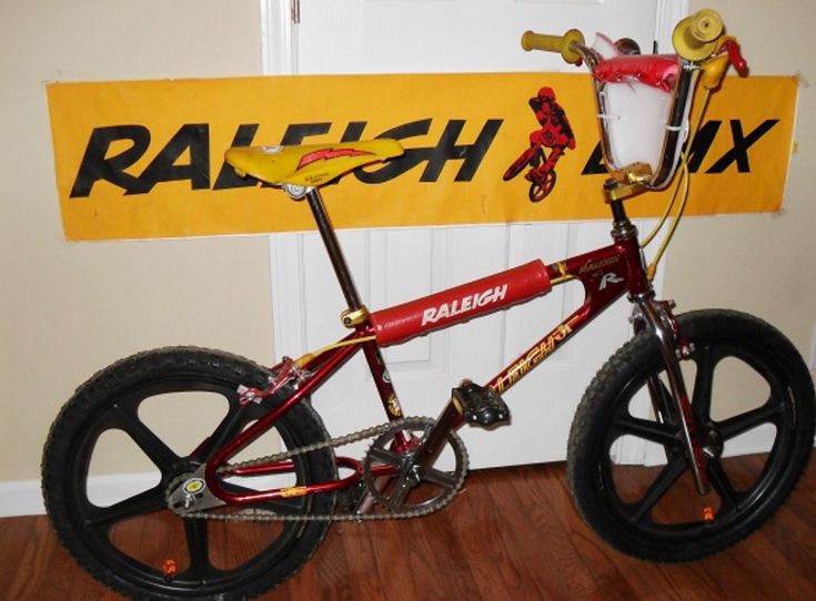 a red and yellow bike parked in front of a sign that says raish mix