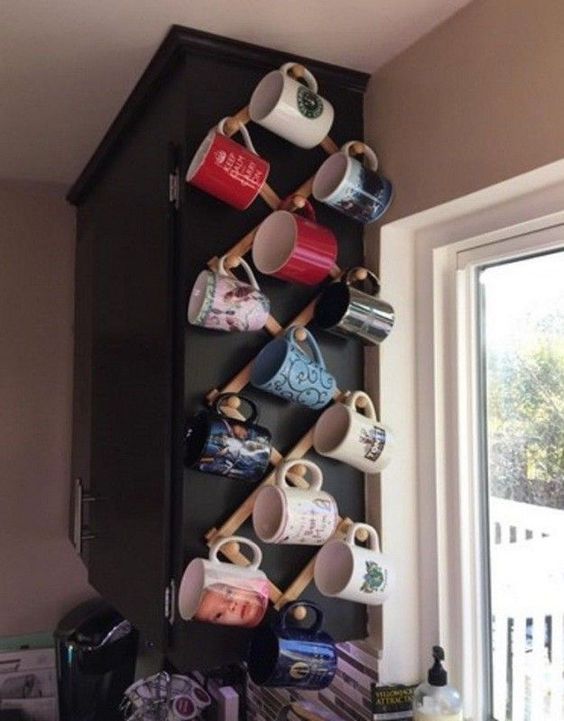 there is a coffee cup holder on the wall in the kitchen with cups hanging from it