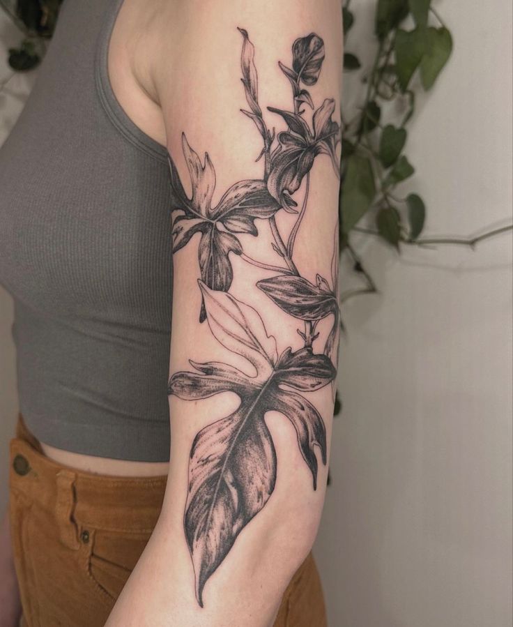 a woman with a tattoo on her arm has a flower and leaves design on it