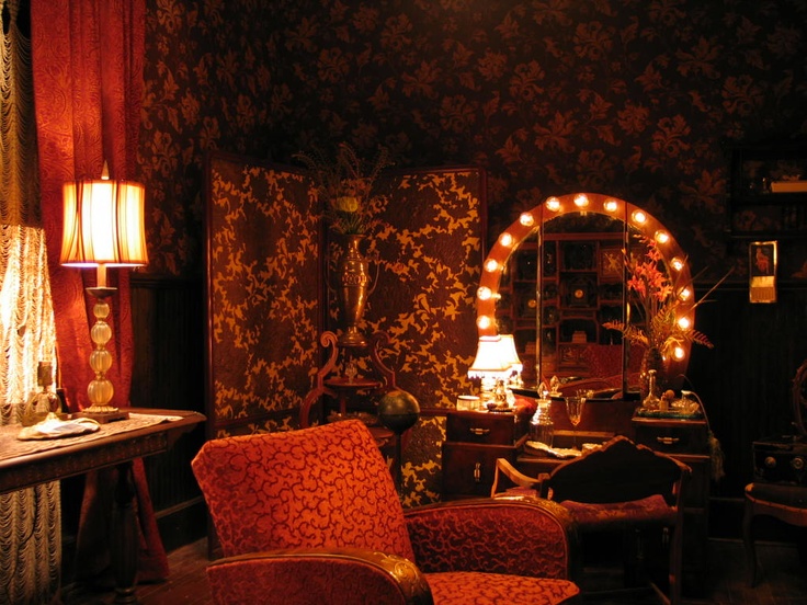 a living room filled with lots of furniture and lights on the wall next to a mirror