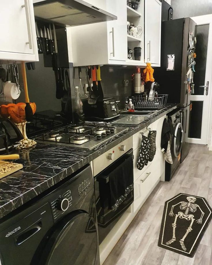 a kitchen with white cabinets and black counter tops is decorated with halloween decorations on the counters