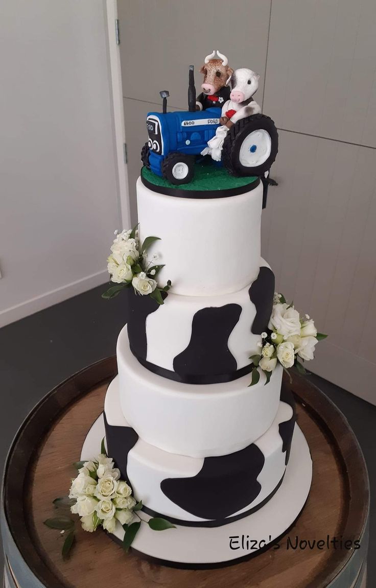 a three tiered cake decorated with black and white cow print is on a wooden platter