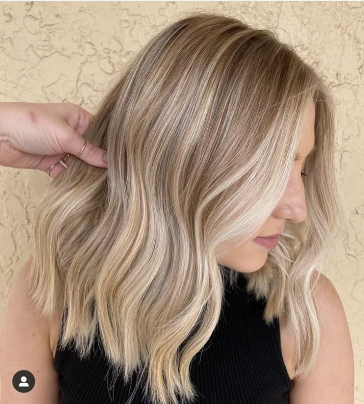 a woman with long blonde hair is getting her hair styled by someone else's hand