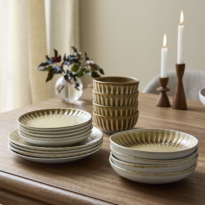 a wooden table topped with plates and candles