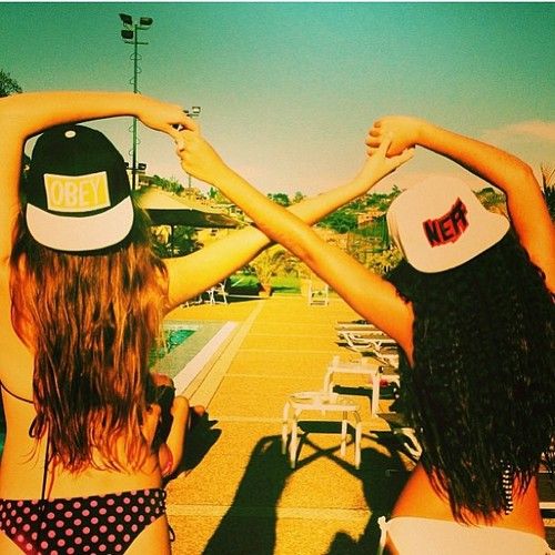 two young women in bikinis and hats are holding their hands up to each other