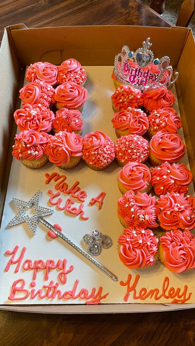 a box filled with cupcakes covered in pink frosting and topped with a tiara