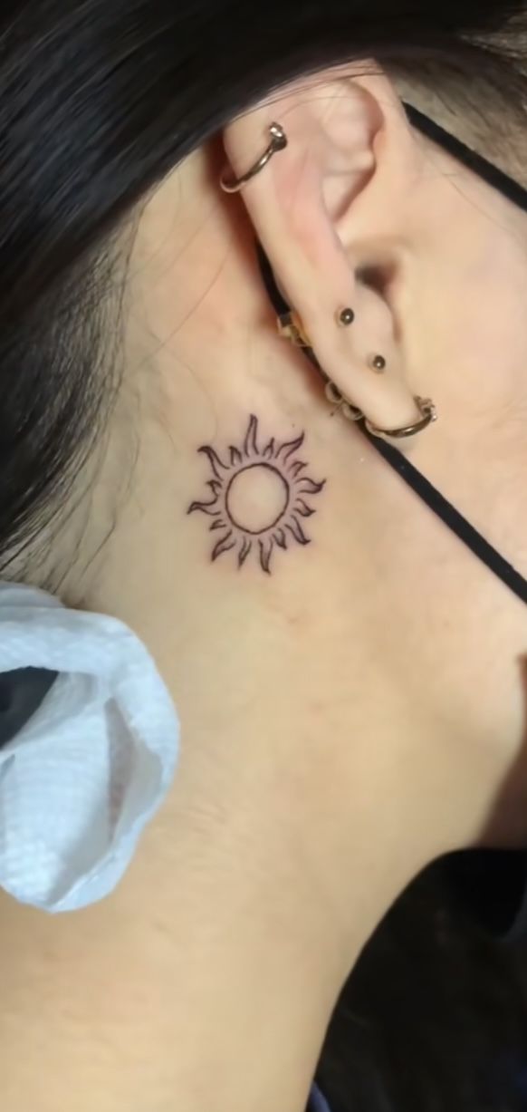 a woman with a sun tattoo behind her ear