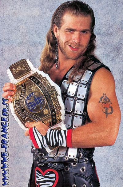 a man with long hair holding a wrestling belt