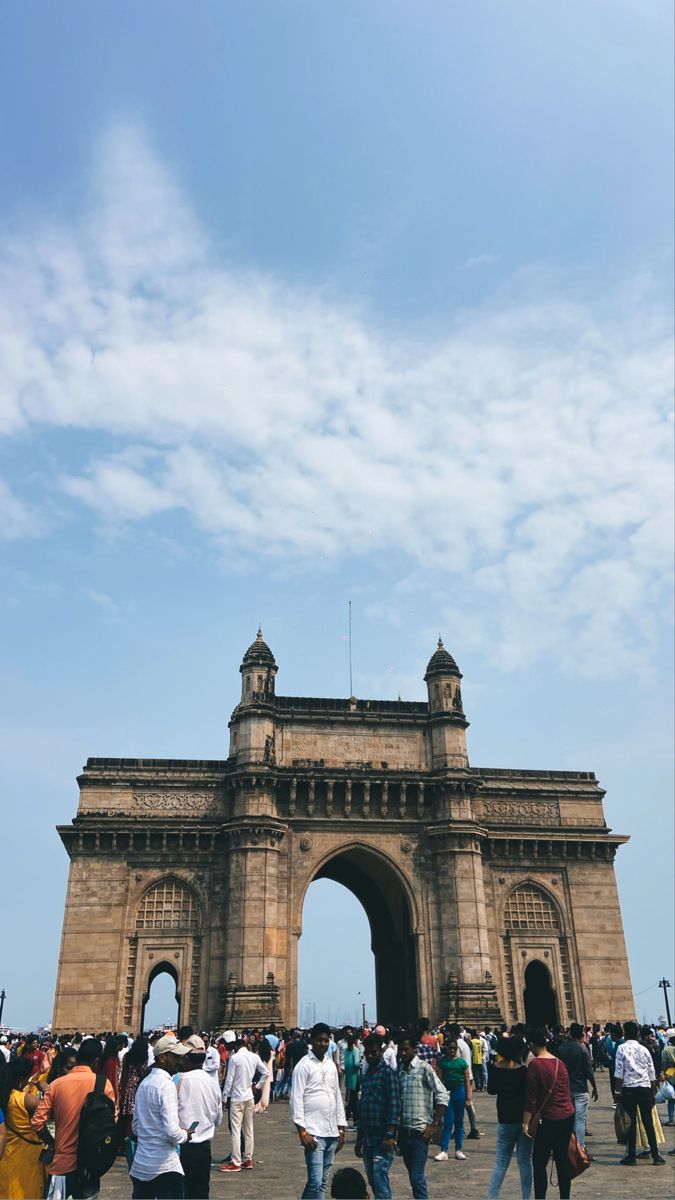 many people are walking around in front of an arch that is built into the sky