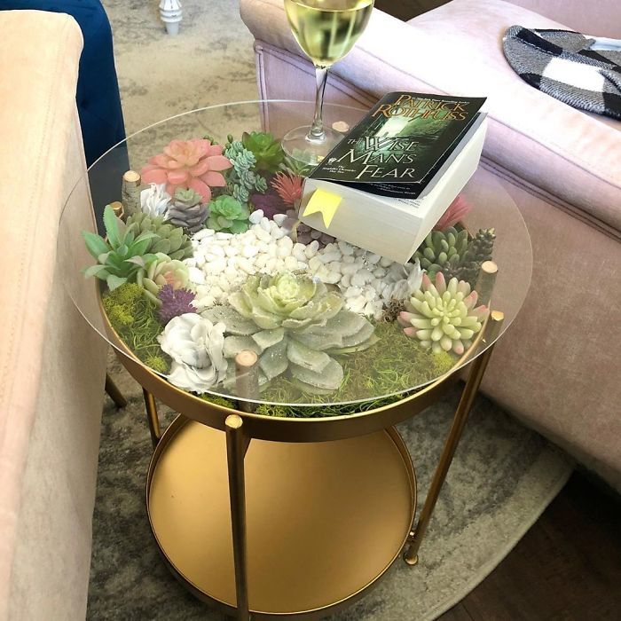 a glass table topped with succulents and a book on top of it