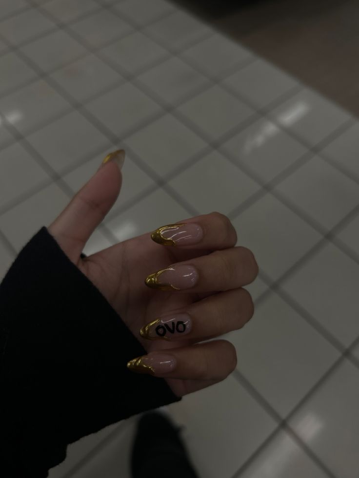 a woman's hand with some gold nail polish on it and the word omg written in black