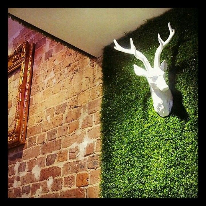 a fake deer's head is mounted to the side of a brick wall with moss growing on it