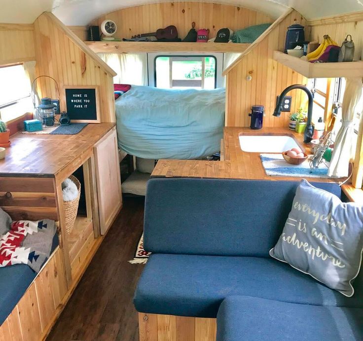 the interior of a camper with blue couches and wooden shelves on each side