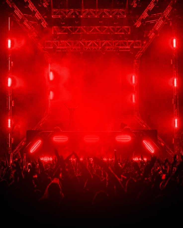 a stage with red lights and people in the audience at a music festival or concert