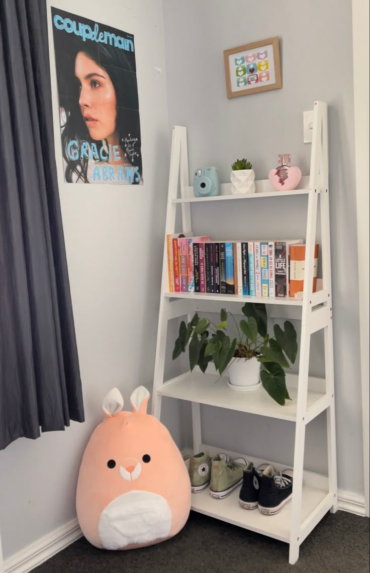 a shelf with books, plants and stuffed animals on it in the corner of a room