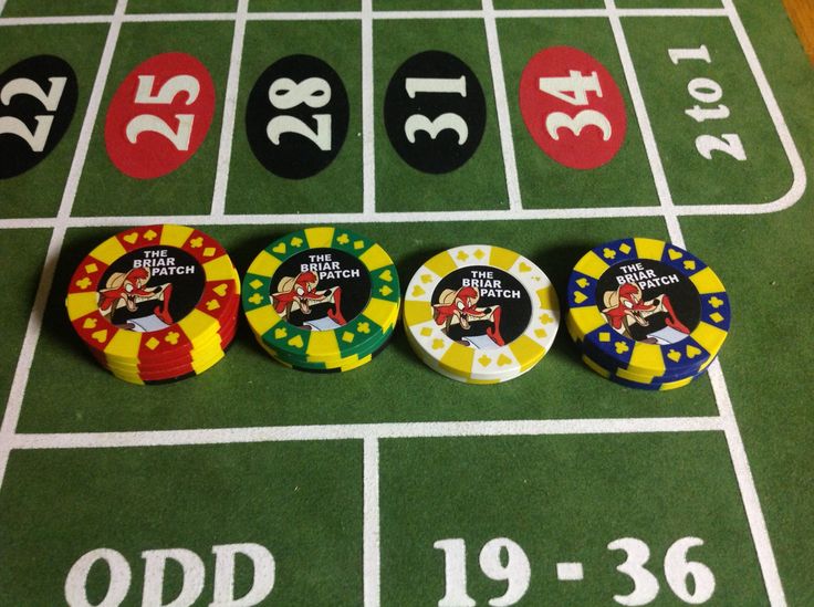 four casino chips sitting on top of a green table next to numbers and dices