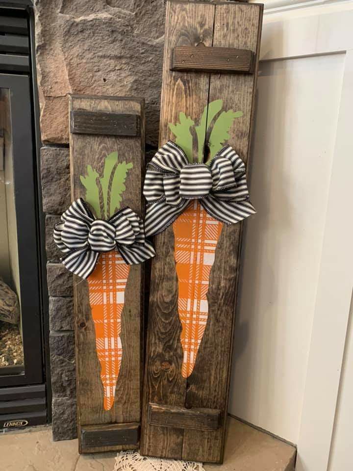 two wooden carrots decorated with black and white ribbon on top of a fireplace mantel