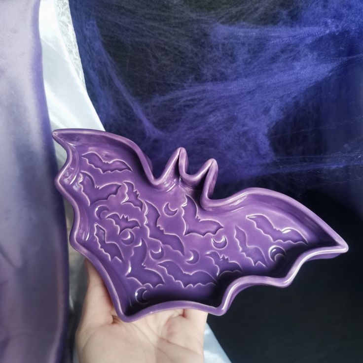 a hand holding a purple bat shaped dish