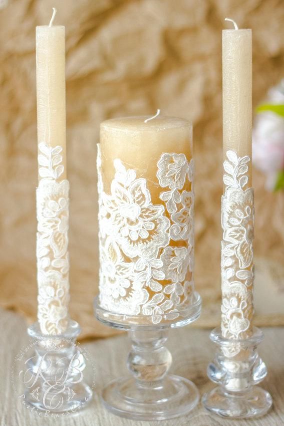 three candles sitting on top of a table next to each other with white lace over them