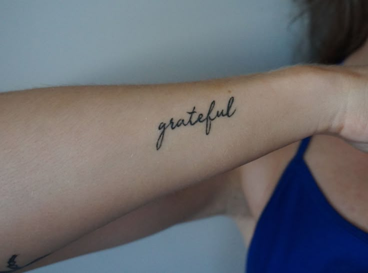 a woman's arm with the word grateful written in cursive writing on it