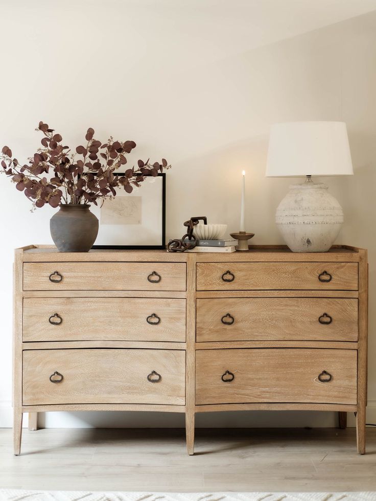 a wooden dresser sitting next to a lamp on top of a hard wood floor