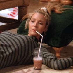 a woman laying on the floor with a straw in her mouth next to a drink