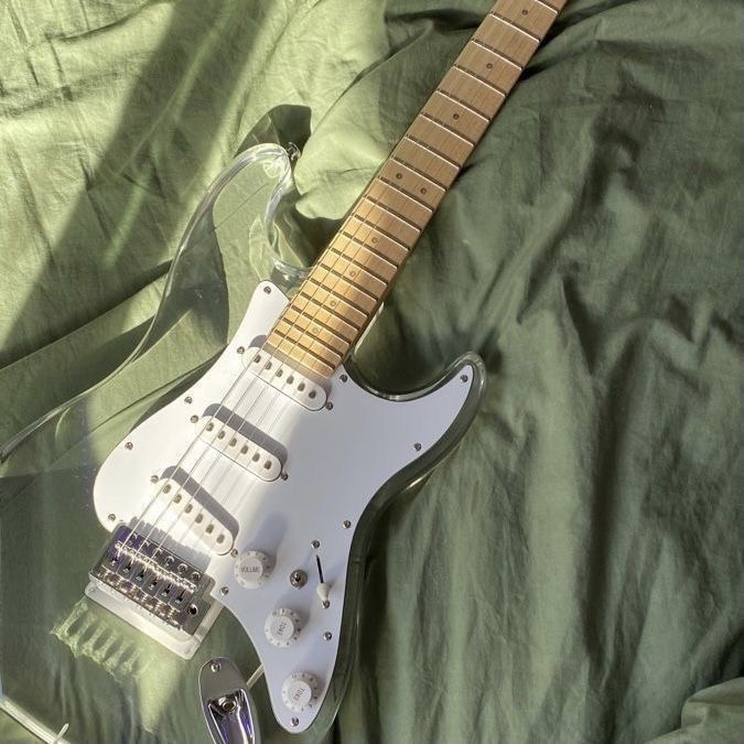 an electric guitar is laying on a green sheet and covered by a plastic case that holds it's strings