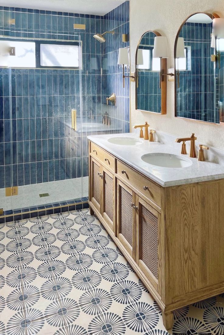 a bathroom with two sinks, mirrors and blue tiles on the floor in front of it