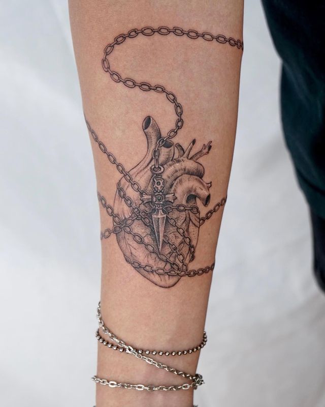 a woman's arm with a tattoo on it and a chain around her ankles