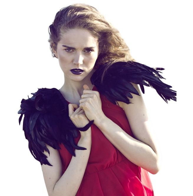 a woman in a red dress with black feathers on her shoulders and arms around her neck