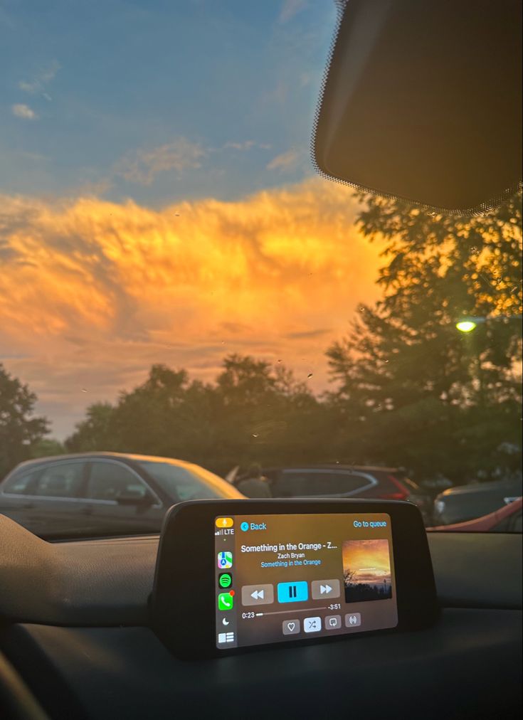 a car dashboard with the sun setting in the background