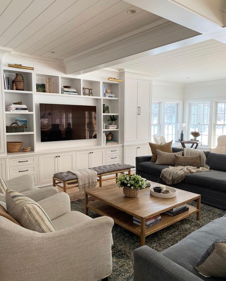 a living room filled with furniture and a flat screen tv mounted on a wall above a wooden coffee table