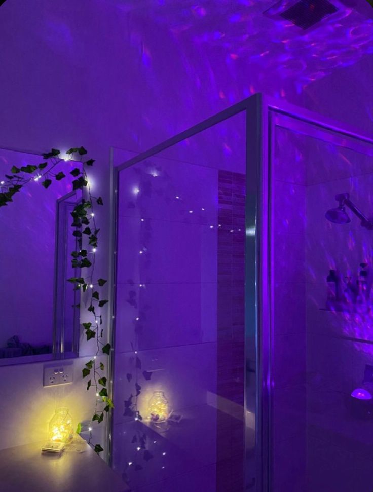 the bathroom is lit up with purple lights and flowers on the shower stall wall, along with candles