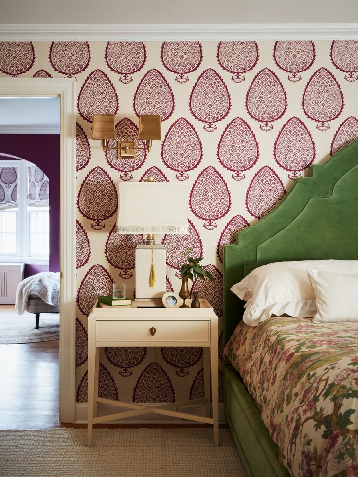 a bedroom with a green headboard and floral wallpaper