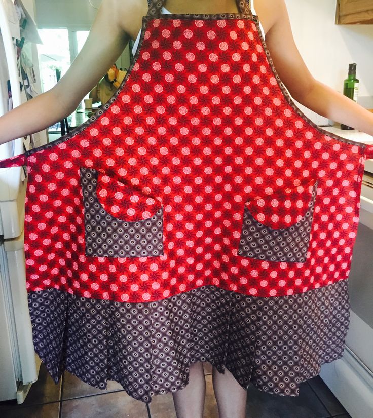 a woman in a red and black polka dot apron is holding her hands behind her back