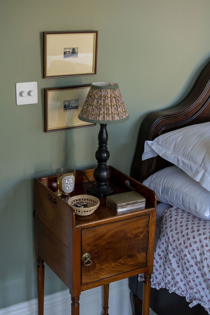 a nightstand with a lamp on top of it next to a bed