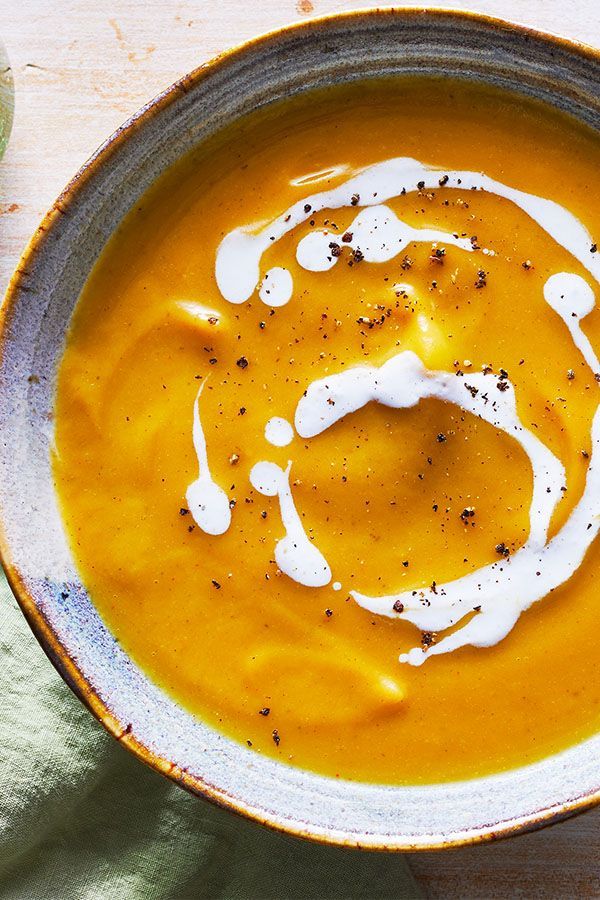 there is a bowl of soup with cream on the table next to a glass of water