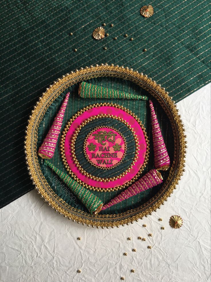 a decorative plate with pink, green and gold designs on the edge is sitting on a table