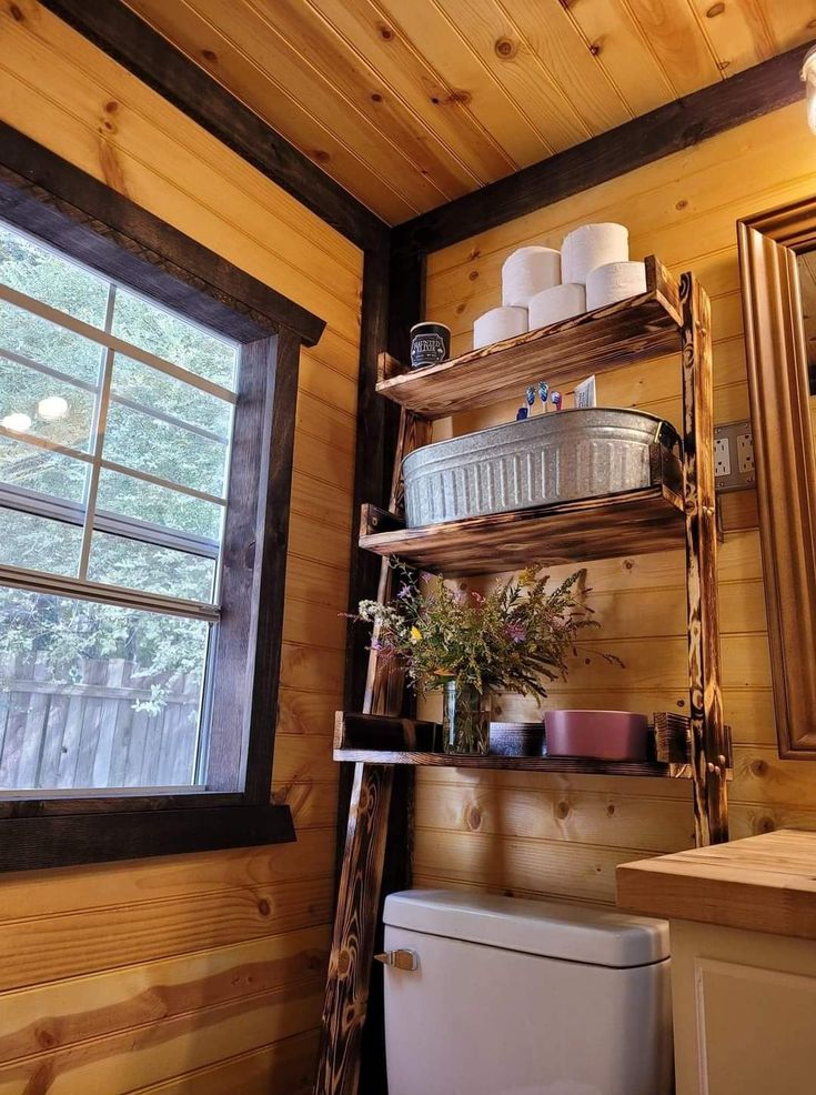 a bathroom with wooden walls and shelves filled with toilet paper