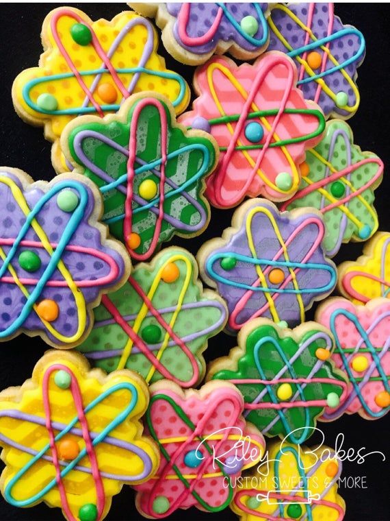 decorated cookies with colorful icing on a black tablecloth are arranged in the shape of an atomic symbol