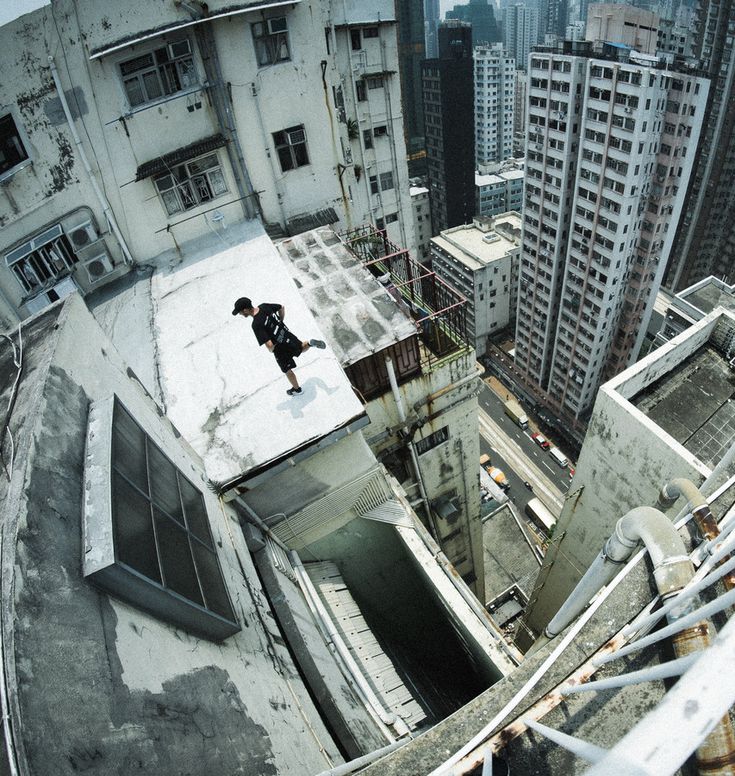 a skateboarder is doing tricks on the edge of a building in an urban area