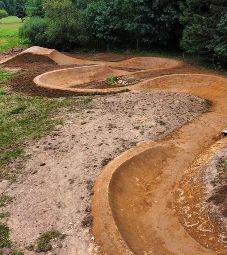 a dirt bike track in the middle of a field with trees and grass around it