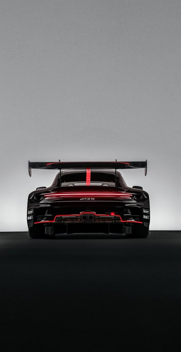 a black and red sports car parked in a dark room with lights on the side