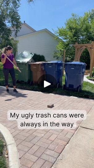 a woman is cleaning the driveway with a mop and some trash can's