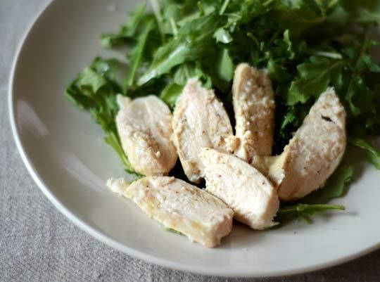 a white plate topped with lettuce and sliced chicken on top of a table