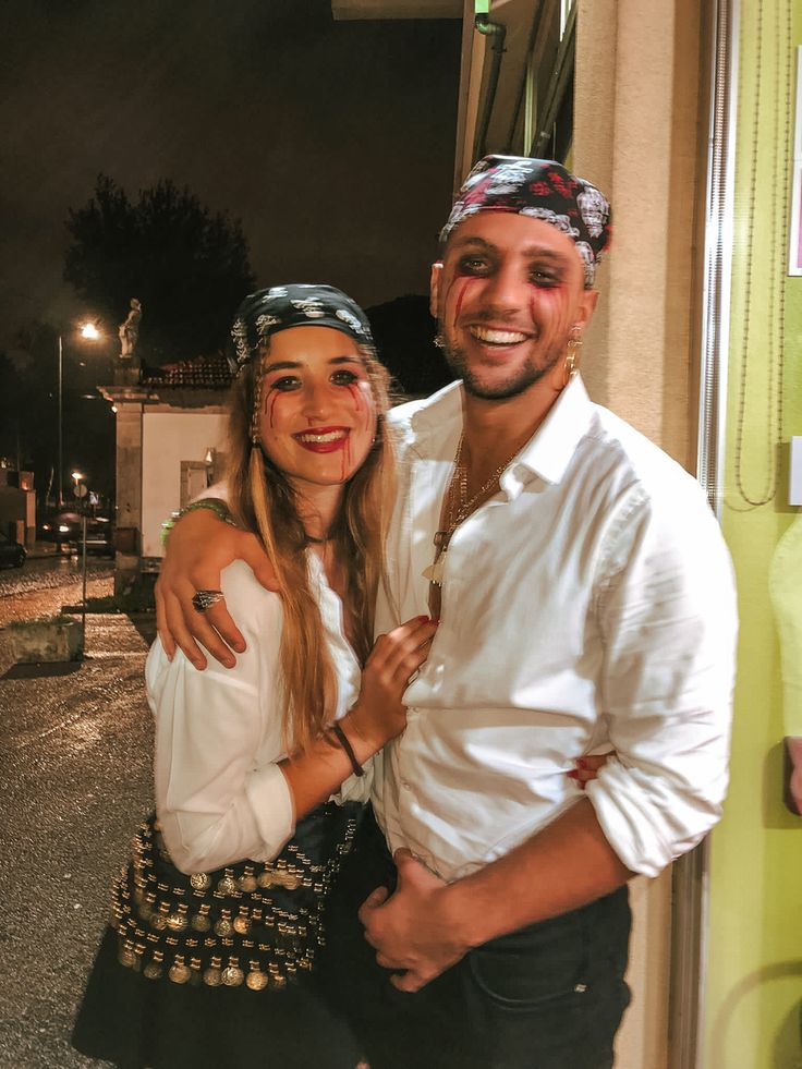 a man and woman standing next to each other in front of a building at night