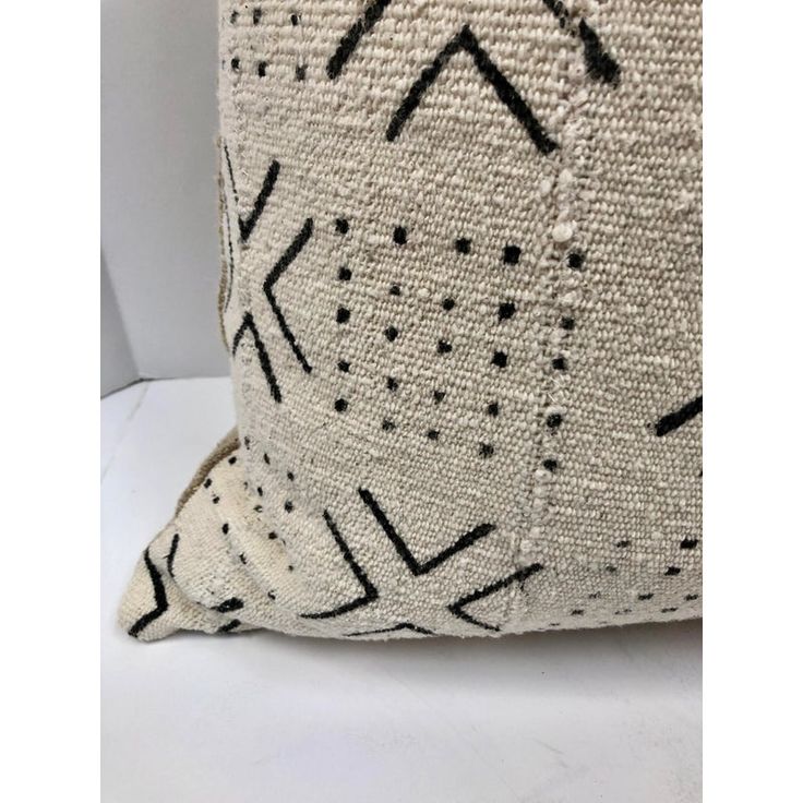 a black and white pillow on a white surface with an arrow design in the middle