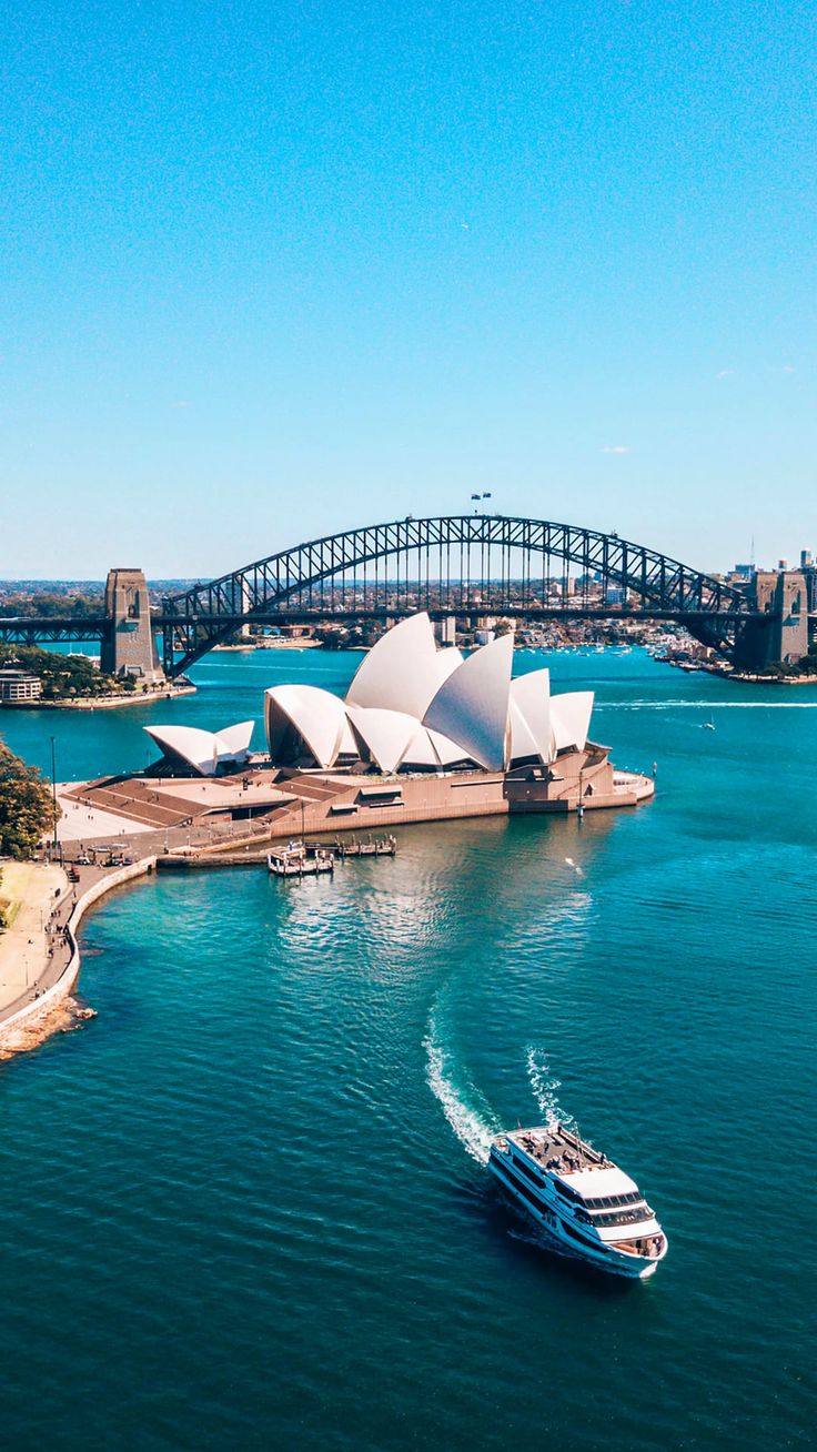 an aerial view of the sydney opera house and harbour bridge, with a boat in the foreground